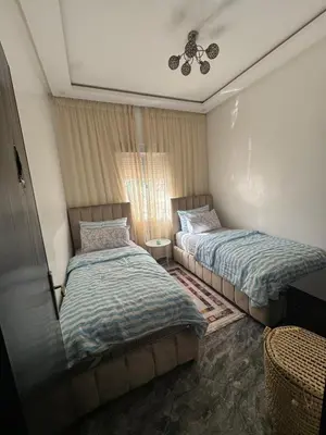a bedroom with two beds and a ceiling fan at Apartment dar bouazza in Dar Bouazza