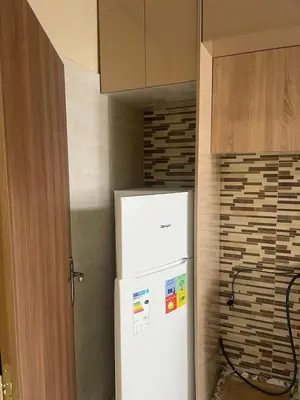a white refrigerator in a kitchen next to a wall at Appartement andalous bouskoura in Bouskoura