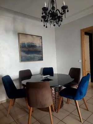 a dining room table with blue chairs and a chandelier at Appartement Familial Casablanca in Casablanca