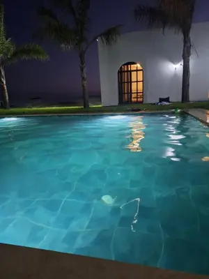 a swimming pool in front of a house at night at Ferme villa in Skhirat