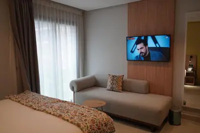 a hotel room with a couch and a tv on a wall at Agdotel Urban Suites in Rabat