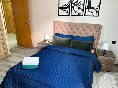 a blue bed with a blue comforter and two lamps at Studio Stade Morocco for family in Mohammedia