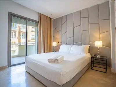 a bedroom with a white bed and a large window at Travel and Leisure - By AppartAli in Casablanca