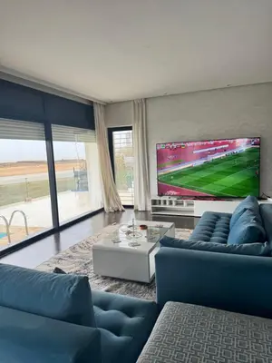 a living room with blue couches and a flat screen tv at Waterfront Villa & Private Pool 12 km from the Stadium in Temara