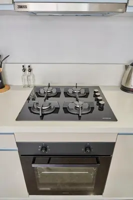a black stove top oven in a white kitchen at AFCON Casablanca 5 min Walk to Stadium Private Terrace 65 inch TV Fiber Internet All Sports Channels in Casablanca