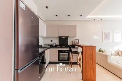 a kitchen with a stainless steel refrigerator in a living room at Aura - 1 BR - Premium Apartment in Maarif