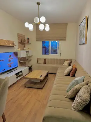 a living room with a large couch and a television at Cozy appartement Rabat Wifak 5min de Harhoura beach in Temara
