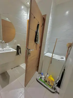 a bathroom with a sink and a wooden door at Cozy appartement Rabat Wifak 5min de Harhoura beach in Temara