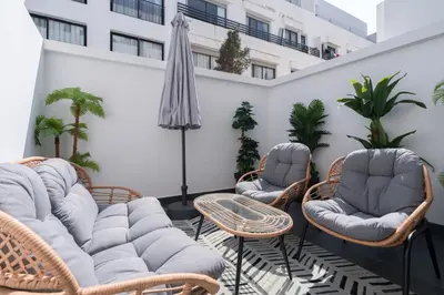 a patio with chairs and tables and an umbrella at 1BR Private Terrace Parking Gym in Casablanca