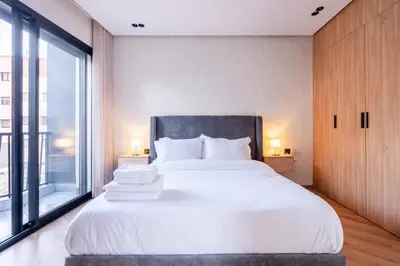 a bedroom with a white bed with a large window at Self Check In 1BR With Gym And Coworking Near CFC in Casablanca