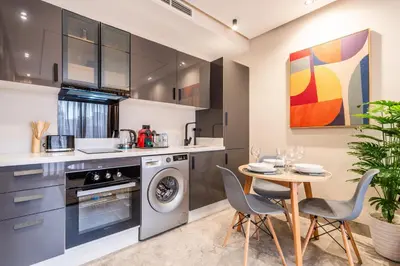a kitchen with a table and chairs and a washing machine at Self Check In 1BR With Gym And Coworking Near CFC in Casablanca