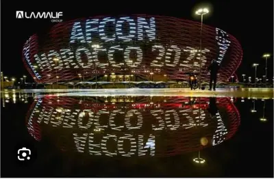 a building with a reflection in the water at night at Baya Residentie in Temara