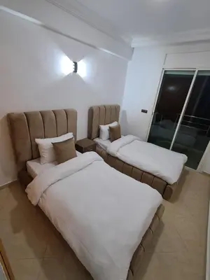 two twin beds in a room with a window at Baya Residentie in Temara