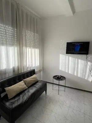 a living room with a black couch and a tv at Cozy getaway for a perfect stay in Rabat
