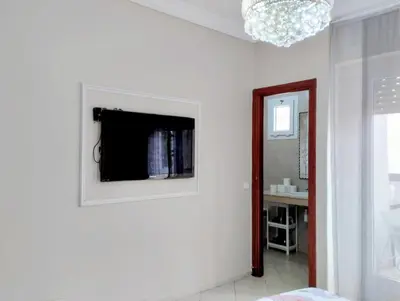 a living room with a television on a white wall at Camera a 2 minuti dal mare e la mosquee Hassan 2 in Casablanca-Port