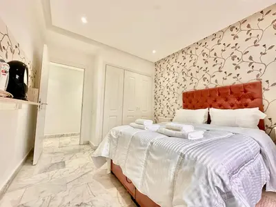 a bedroom with a large bed with a red headboard at Elegant apartment in Nouaceur, Close to Airport in Nouaseur
