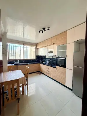 a kitchen with wooden cabinets and a table and a dining room at Beautiful Apartment for Rent in Corniche de Rabat in Rabat