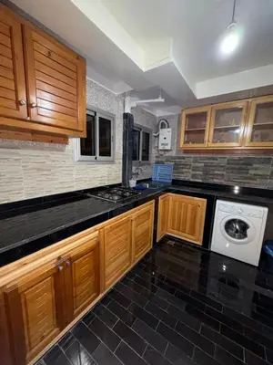 a kitchen with wooden cabinets and a washer and dryer at Appartement idéal pour la CAN à 5 min du stade Moulay Abdellah in Rabat