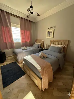 two beds in a bedroom with red curtains at Appartement cosy 2 chambres à Agdal, à 5 min de la Gare in Rabat