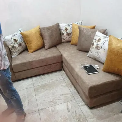 a brown couch with pillows and a laptop on it at Appt Mansbay beach in Mansouria