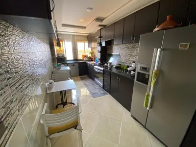 a kitchen with a refrigerator and a table and chairs at Appartement prestigieuse en plein cœur de Hay Riad et près du stade Moulay Abdallah in Rabat