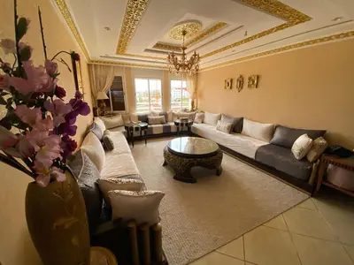 a living room with couches and a vase with flowers at Appartement prestigieuse en plein cœur de Hay Riad et près du stade Moulay Abdallah in Rabat