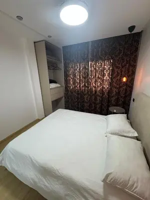 a bedroom with a large white bed and a wall at Modern Cozy Studio with Open-Plan Kitchen near All Amenities Rabat in Rabat