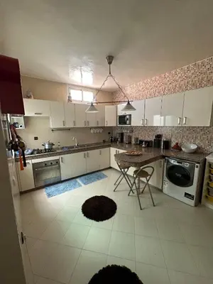 a kitchen with white cabinets and a table in it at Appartement 500 m from Moulay Abdellah Stadium in Temara