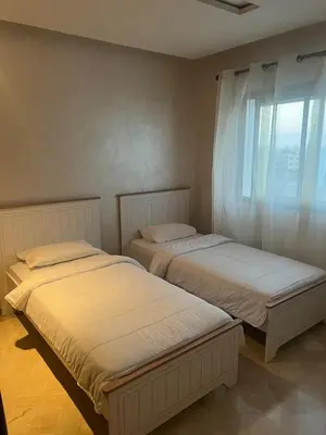 two beds in a room with a window at Appartement en bord de Mer in Mohammedia