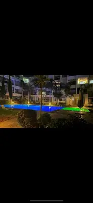 a night view of a parking lot with a palm tree at Appartement en bord de Mer in Mohammedia