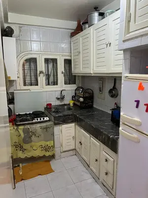 a kitchen with white cabinets and a stove and a refrigerator at Location des appartements souf in Temara