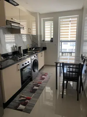 a kitchen with a stove and a table with a washing machine at Apartment in a residence with pool in Mohammedia