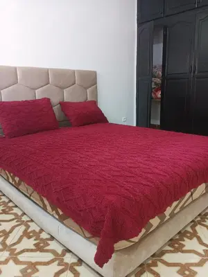 a bedroom with a large bed with a red comforter at Appartement temara in Temara