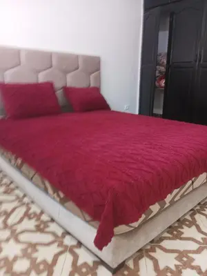 a bedroom with a large bed with a red comforter at Appartement temara in Temara