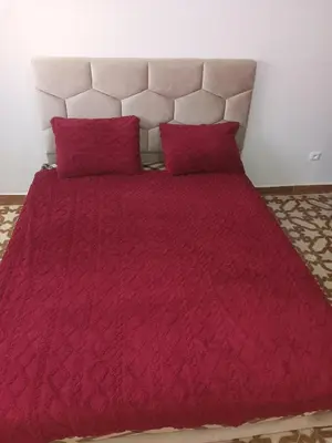a bed with a red comforter and two red pillows at Appartement temara in Temara