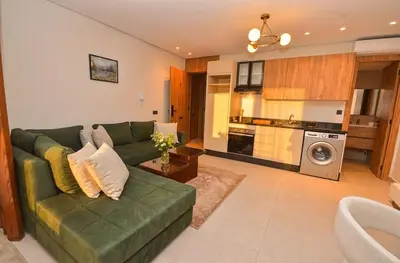 a living room with a green couch and a kitchen at Studio 01 Maarif - High Speed Wi-Fi in Casablanca