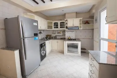 a kitchen with a stainless steel refrigerator and white cabinets at Grand 3 pièces de standing, confort premium in Casablanca