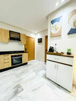 a kitchen with white marble flooring and wooden cabinets at Studio cosy et calme, idéal pour se détendre 15 in Casablanca