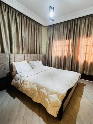 a bedroom with a large bed in front of curtains at Appartement confortable à Rabat, idéalement situé près de la Corniche et du Stade in Rabat