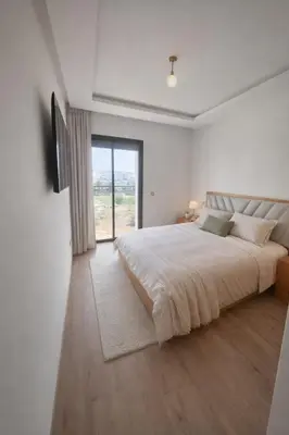 a white bedroom with a large bed and a window at Central Modern Apartment Agdal TGV Train Station in Rabat