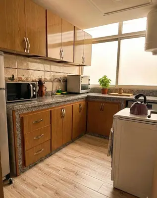 a kitchen with wooden cabinets and a sink and a refrigerator at Séjour économique près de la plage in Bouznika
