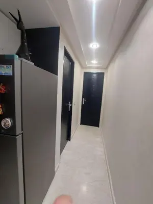 a hallway with two black doors and a hallway with a refrigerator at Cocon & Confort in Dar Ben Abdallah Ben Dehbi