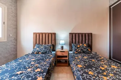 a bedroom with two beds and a table with a lamp at Rihab's House in Casablanca