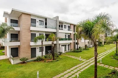 an apartment building with palm trees in front of it at Cosy 2 Bedrooms Skhirat Residence in Skhirat