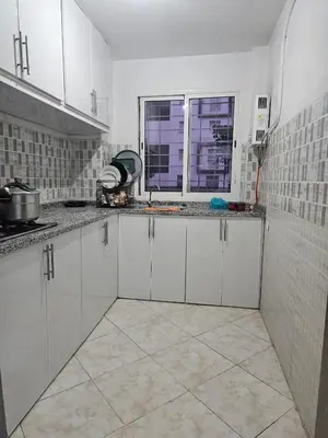 a white kitchen with white cabinets and a window at Bouznika in Bouznika