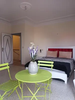 a bedroom with a bed and a green table and chairs at Villa stade Moulay Abdellah in Temara