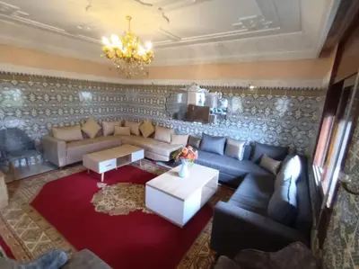 a living room with a couch and a chandelier at Villa stade Moulay Abdellah in Temara