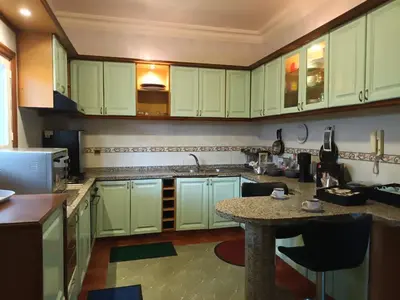 a kitchen with green cabinets and a table in it at Villa stade Moulay Abdellah in Temara