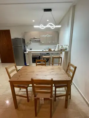 a dining room table with chairs and a kitchen at Appartement Piscine Gare Oasis in Casablanca