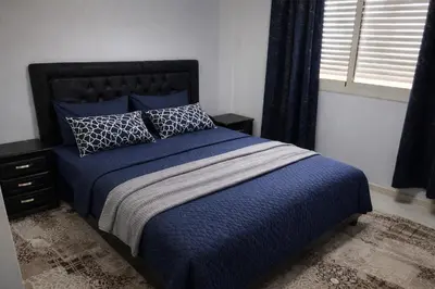 a bedroom with a bed with blue sheets and pillows at Appartement Bouskoura 15 min de l'aéroport mohamed 5 in Casablanca